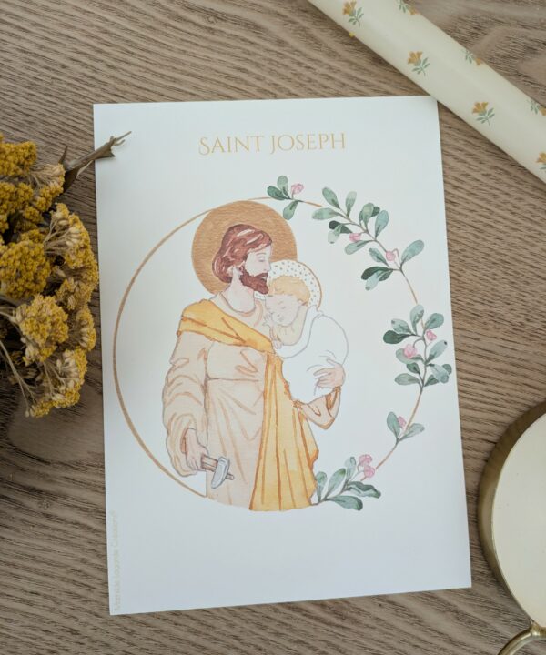 Affiche A5 d'une illustration peinte à la main représentant saint Joseph artisan tenant l'enfant Jésus dans ses bras, entourée d'une couronne florale.