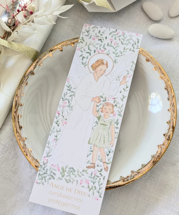 Signet marque-page représentant un ange gardien veillant sur une petite fille qui lui tient la main, entourés de feuillages et de baies roses Avec sa courte prière à l'ange gardien, c'est idéal en cadeau de naissance, de baptême ou pour marquer les pages d'un livre.
