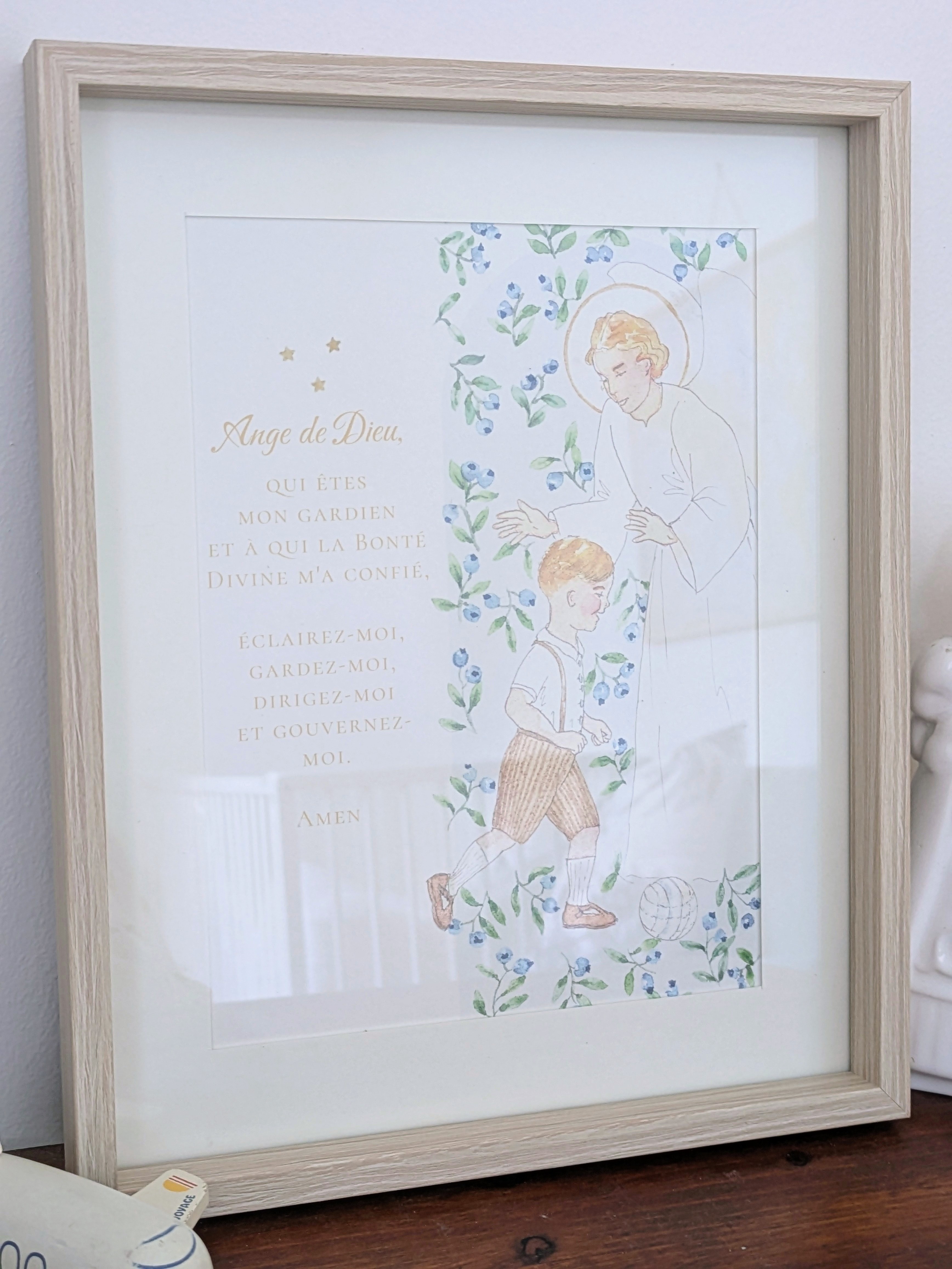 Affiche A5 encadrée représentant un petit garçon courant derrière un ballon, et sur lequel veille son ange gardien, avec motifs floraux. Affiche peinte à la main.