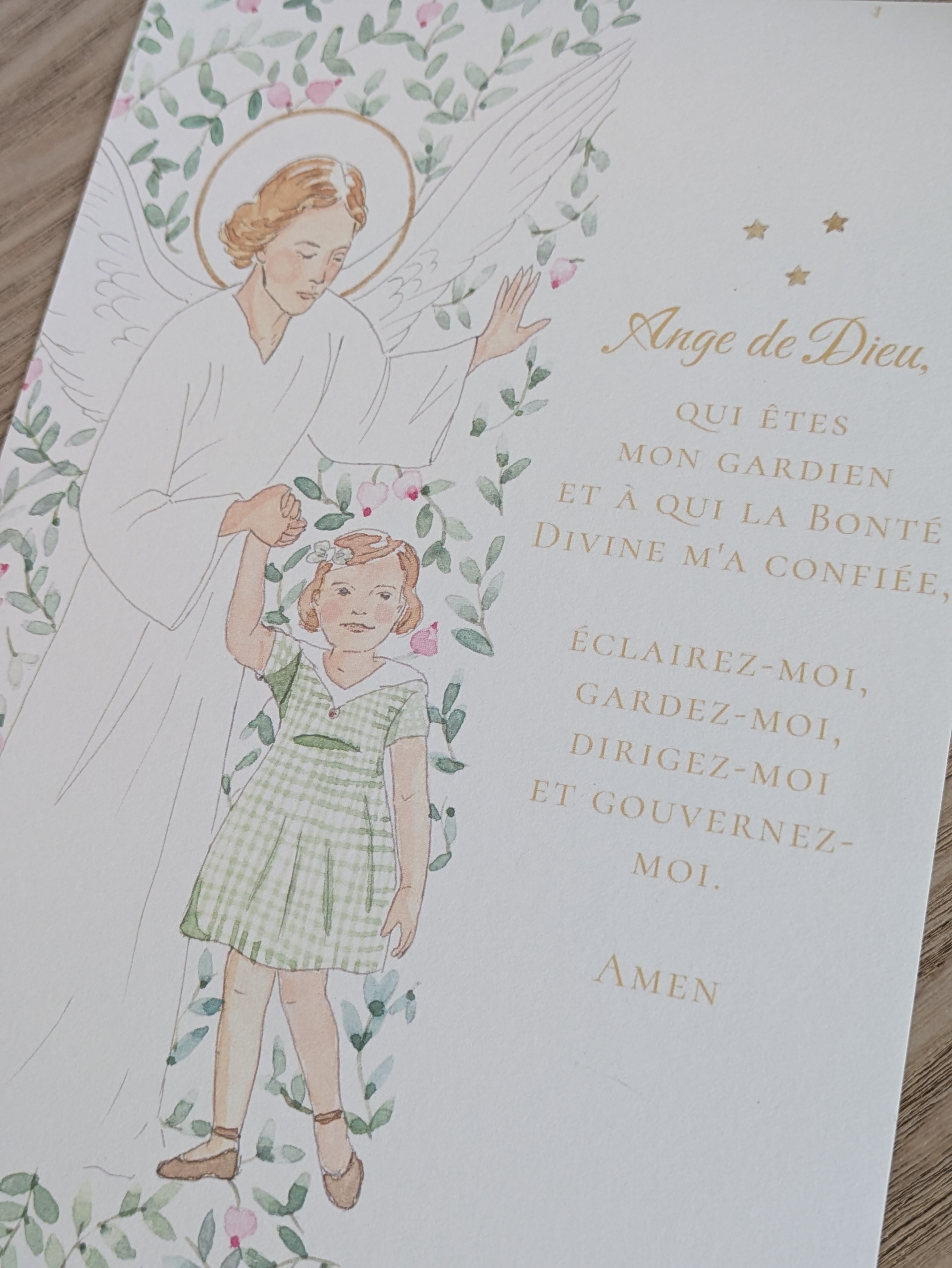 Affiche A5 illustrée à l'aquarelle et reproduite sur papier épais texturé, avec une petite fille tenant la main à son ange gardien avec prière à lire - Affiche A5 d'une petite fille tenant la main à son ange gardien, entourés de baies roses et feuillages peints à l'aquarelle.