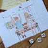 Carte Merci Maîtresse fin d'année scolaire avec un garçon et une fille assis sur un bureau d'écolier, dans leur salle de classe. Idéale pour accompagner un cadeau de remerciement à la maitresse, au maître ou à l'atsem.