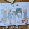 Carte Merci Maîtresse fin d'année scolaire avec un groupe d'enfant en uniforme d'écolier debouts et dans un décor de salle de classe. Ils tiennent chacun une pancarte. Idéale pour accompagner un cadeau de remerciement à la maitresse, au maître ou à l'atsem.